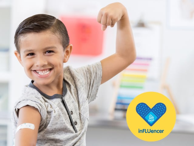 A white boy with brown hair flexes his muscle and shows a bandage on his arm.