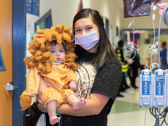 Children's Mercy nurse holds a infant patient in a lion costume.