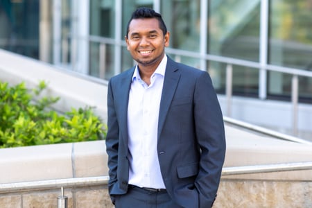 Shehan it button up shirt and navy blue suit standing outside 