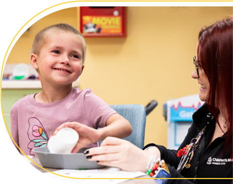 Children's Mercy patient, Parker, smiling while doing an activity with a Children's Mercy staff member..