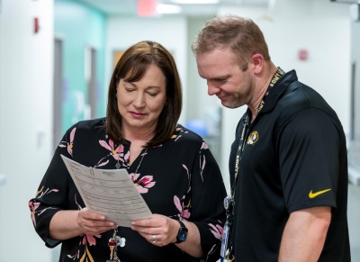 A man and a woman look at a printed report together.