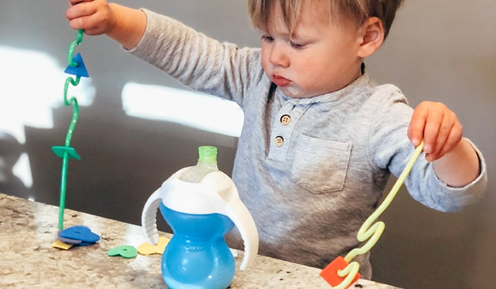 Toddler playing with cups and straws