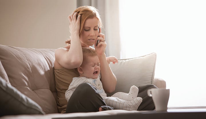 Mom on the phone frustrated while baby is crying