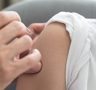 Preteen girl smiling while receiving vaccine shot. 