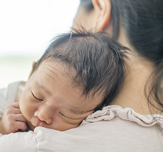 Newborn baby resting on mom's shoulder