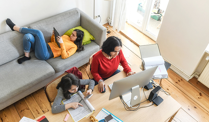 mom working at home and two children doing schoolwork next to her