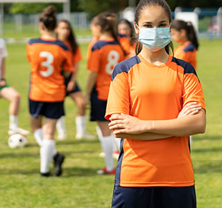 soccer player female wearing a face mask arms crossed