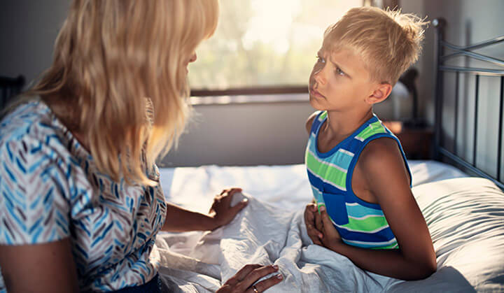 child sick in bed with mom helping