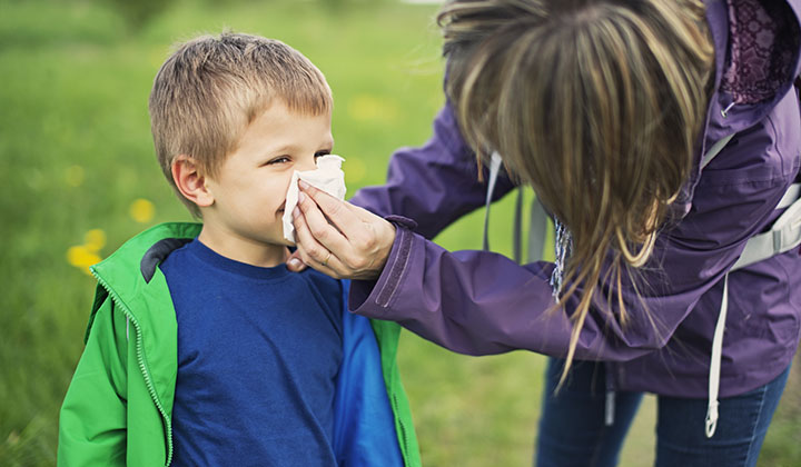 Mom using tissue on son's nose