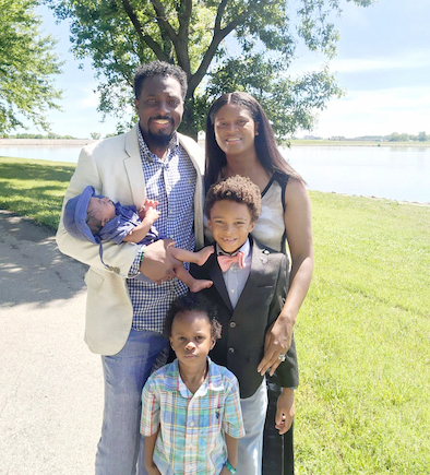 The Walker Family poses by a lake. The family includes dad Tyrelle, mom Aisha, and children Princeton, Cairo and Walker.